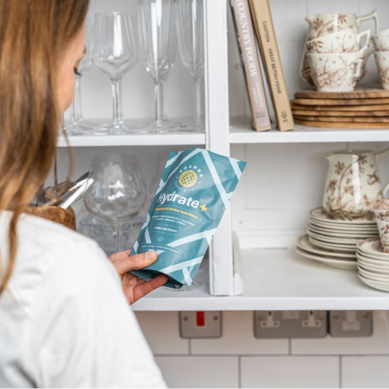 Frau steht in der Küche und sieht sich die Hydrate+ Packung an.
